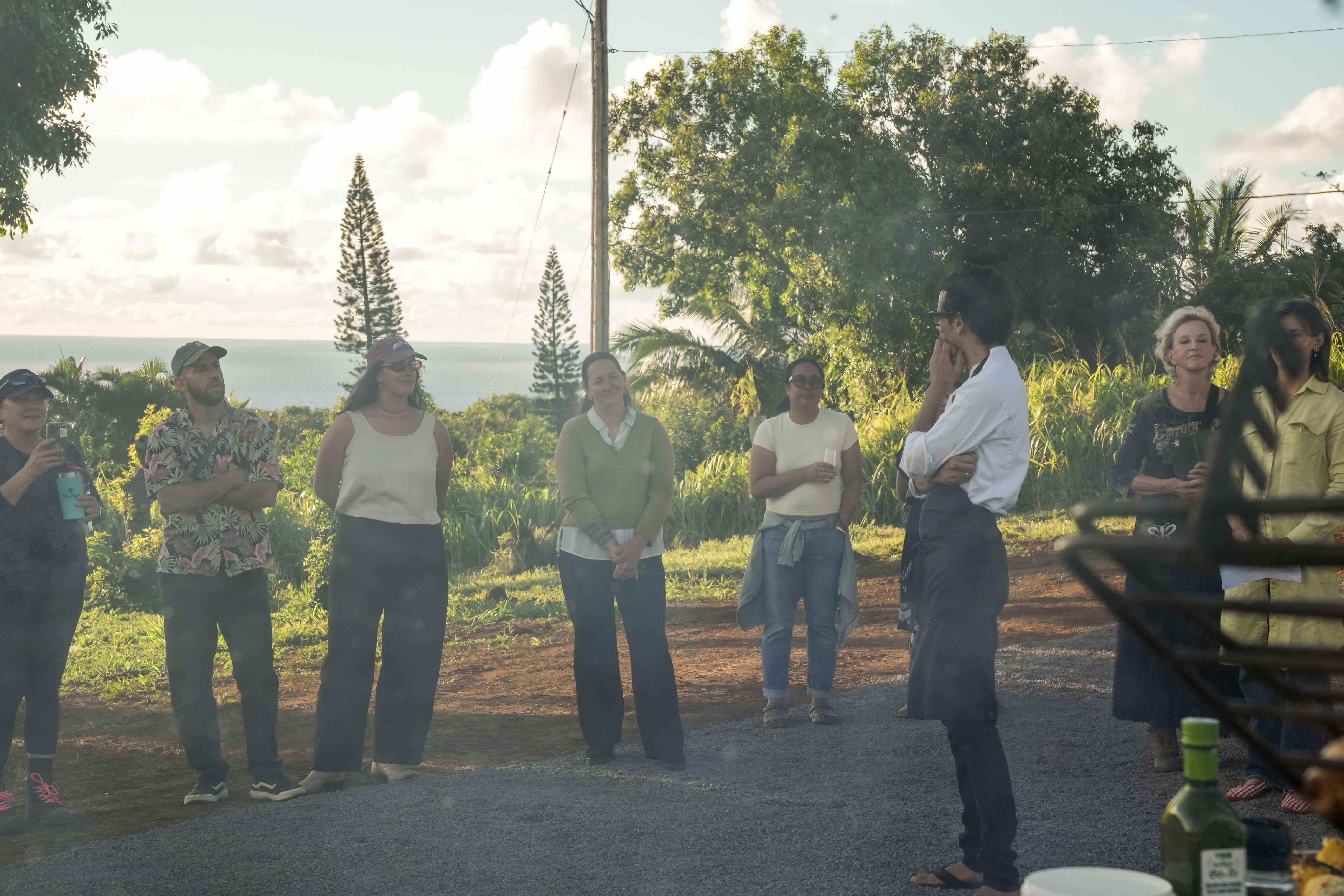 Chef Agustin welcoming a class of guests on the farm at golden hour, the ocean behind