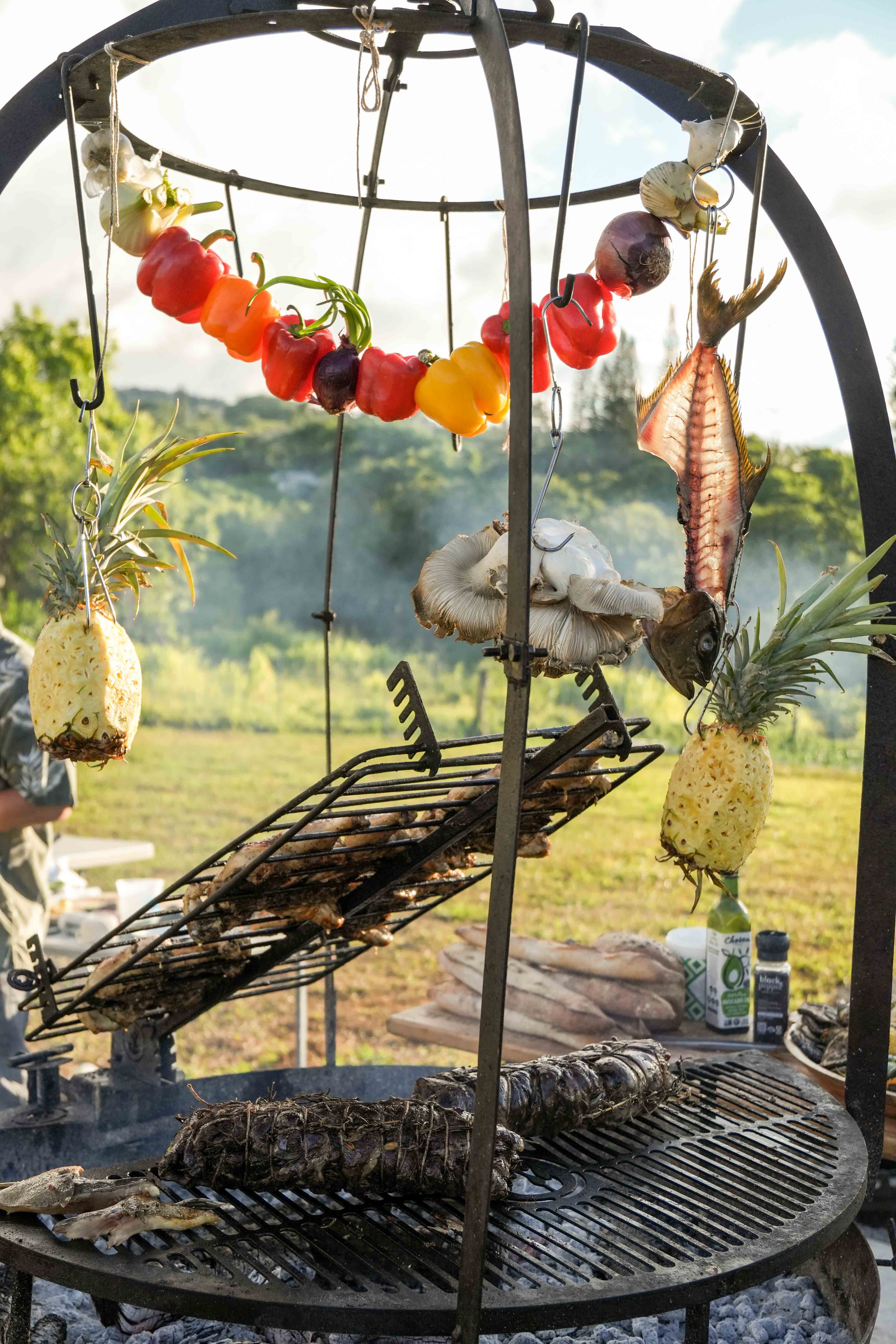Peppers, pineapple, and fish hanging over the live fire